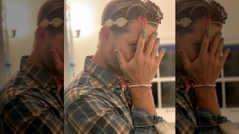 Ben McKenzie holds his hand in front of his face to show off his blue fingernail polish and bracelets.