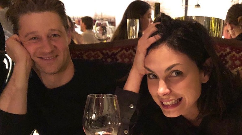 Ben McKenzie places his arm around Morena Baccarin in a restaurant booth.