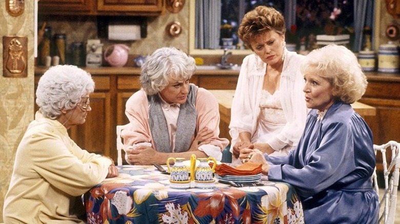 The Golden Girls gather around a cheesecake