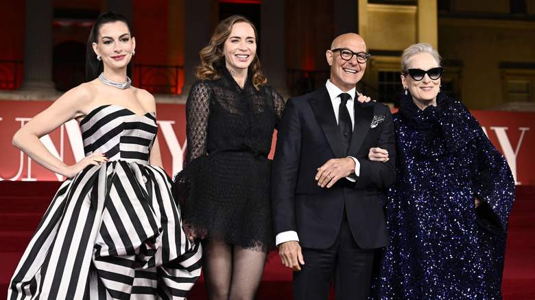 Anne Hathaway, Emily Blunt, Stanley Tucci, and Meryl Streep smiling together.