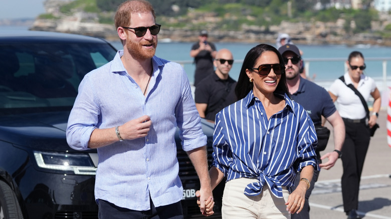 Prince Harry and Meghan Markle walking hand in hand and smiling