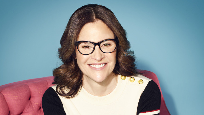 Ally Sheedy smiling in a red chair