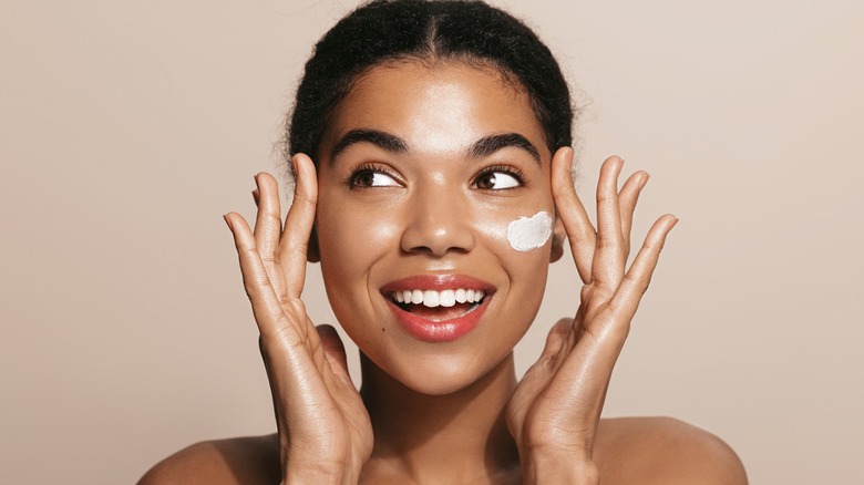 woman putting moisturizer on face