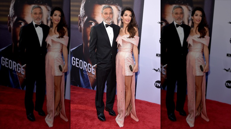 George Clooney with his arm around the waist of wife Amal Clooney.