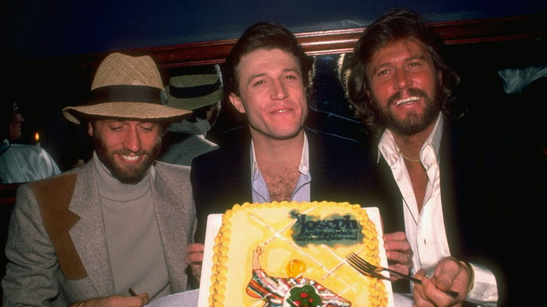 From left: Maurice, Andy, and Barry Gibb celebrating Andy's Broadway debut with a Joseph and the Technicolor Coat cake in 1982