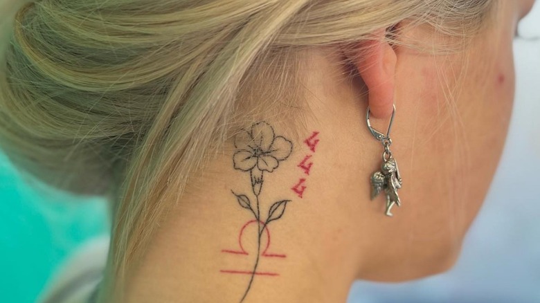 Blonde woman with 444 tattoo behind the ear