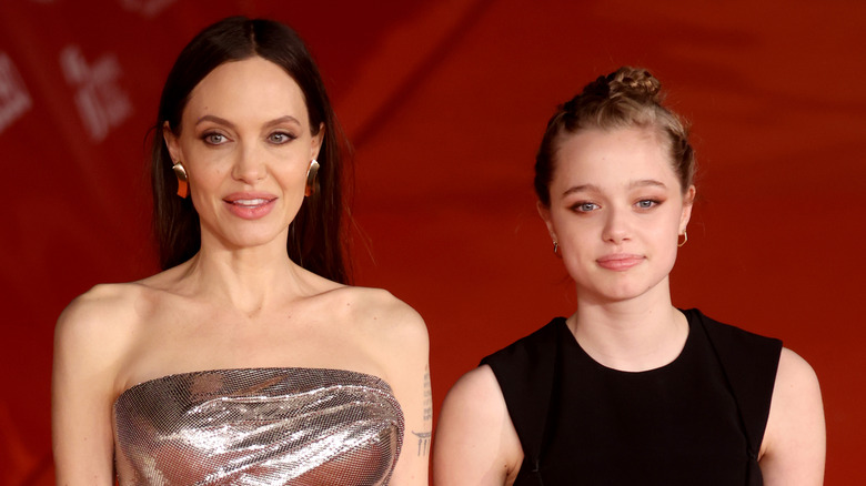 Angelina Jolie and daughter Shiloh with a red background