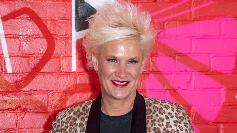 Anne Burrell in front of red painted brick wall