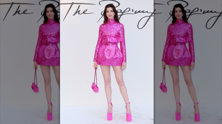 Anne Hathaway posing in a short pink dress and high heels