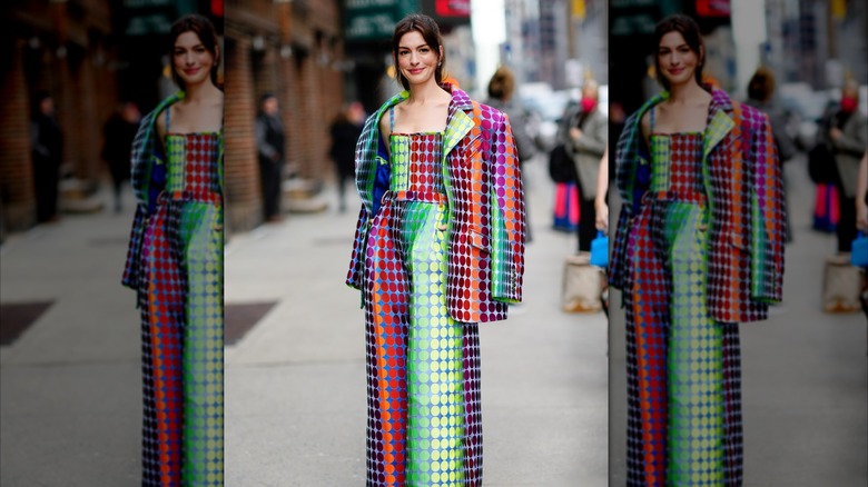 Anne Hathaway posing in a colorful jacket and jumpsuit