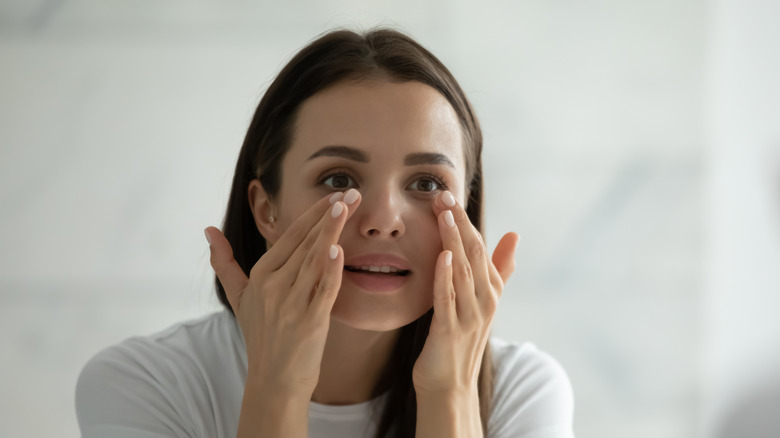 A woman dabbing underneath her eyes 