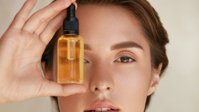 A woman holding serum in front of her face 