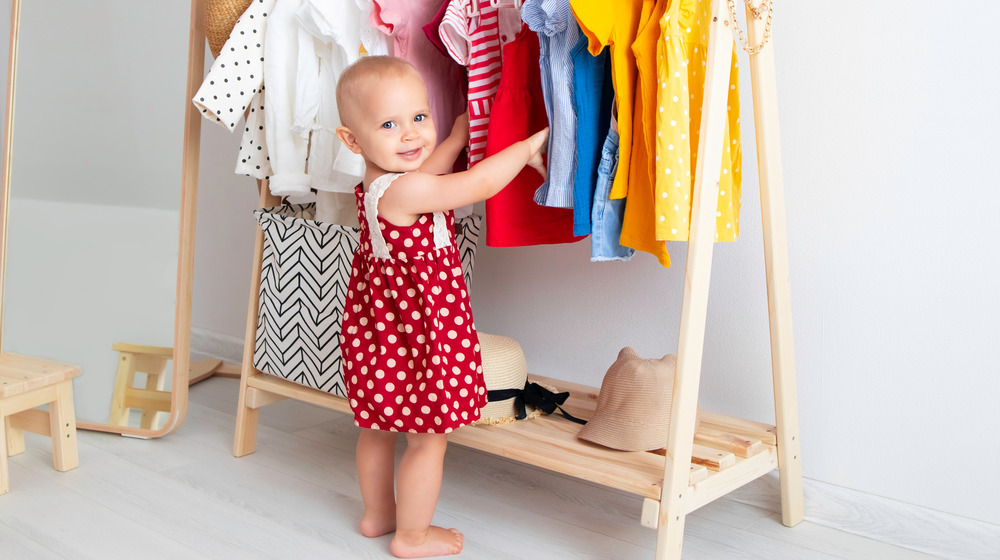Baby standing by clothes