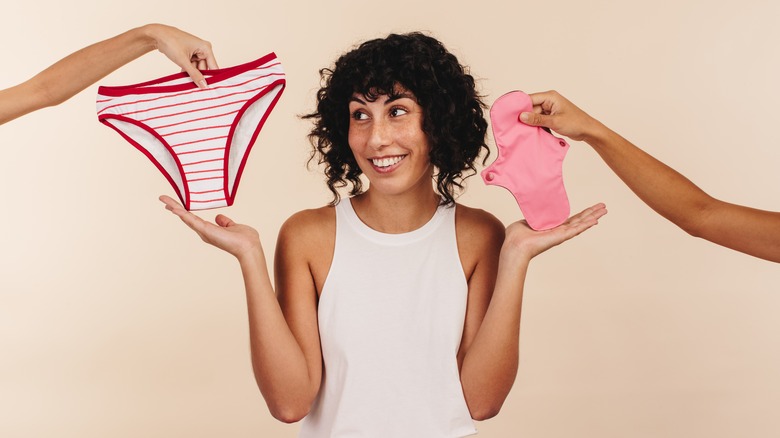 A woman holding up two pairs of period underwear