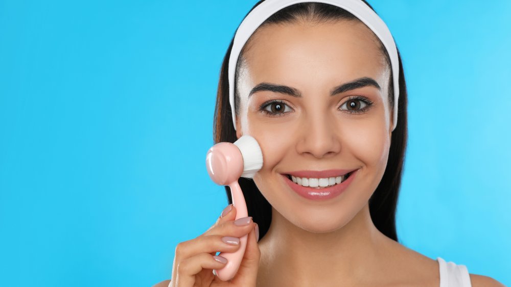 Woman using facial cleansing brush