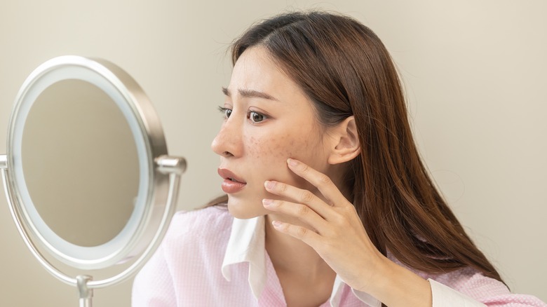 Woman looking at freckles in mirror