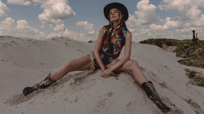 Woman in western gear relaxing on the sand