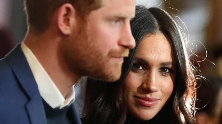 Prince Harry and Meghan Markle pose at an event. 