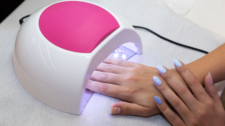 A woman drying her gel nails under a UV lamp
