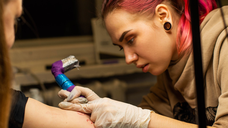 Tattoo artists giving client a new tattoo