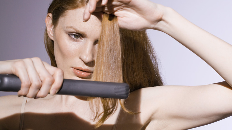 Woman straightening section of hair