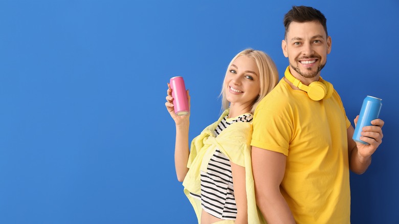 Couple holding soda cans