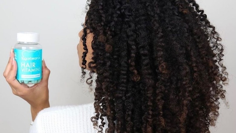 A girl holds Sugarbear Hair Vitamins