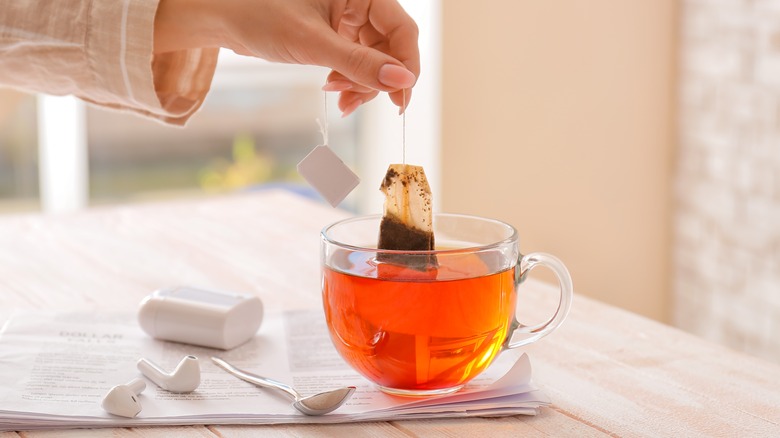Hand holding tea bag in cup