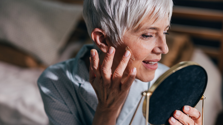 Older woman putting on makeup