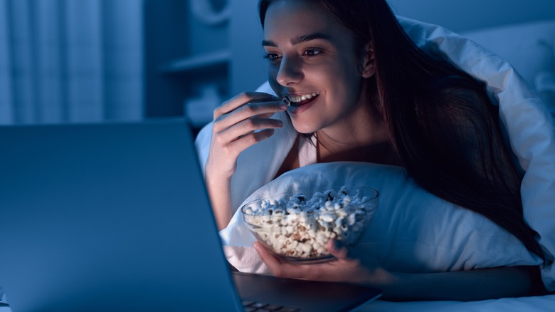 Woman eating popcorn in bed