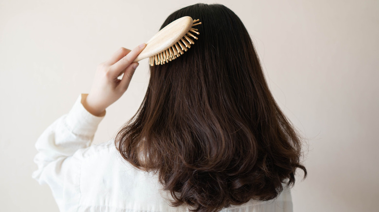 Woman holding a hair brush in front of her eye