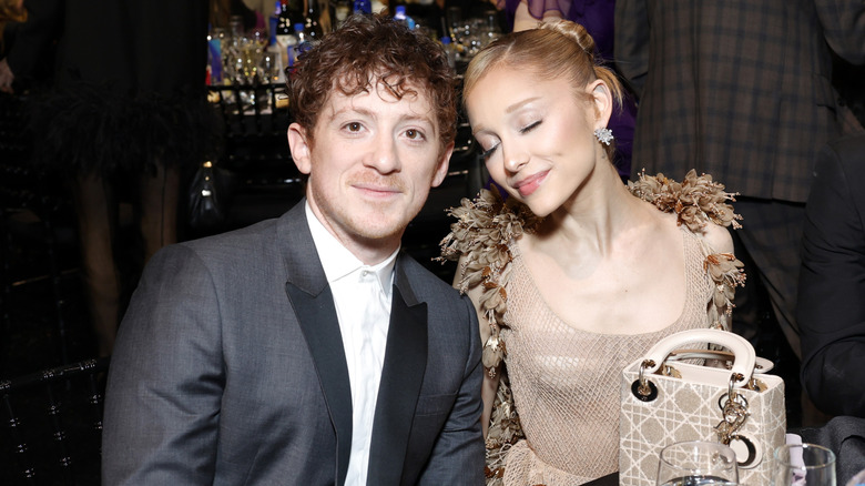 Ariana Grande and Ethan Slater smiling while posing together at an event