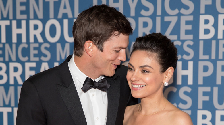 Ashton Kutcher and Mila Kunis smiling while posing at a black-tie event together