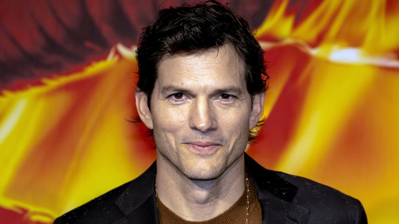 Ashton Kutcher slightly smiling while posing at an event