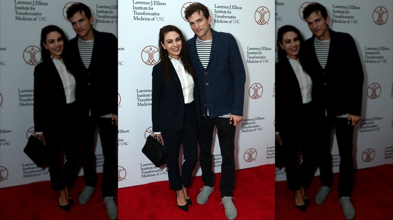 Mila Kunis and Ashton Kutcher smile while posing together at an event