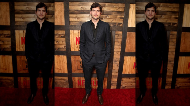 Ashton Kutcher posing in a dark gray suit