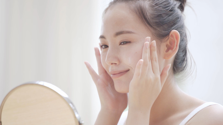 A woman inspecting her skin in a mirror