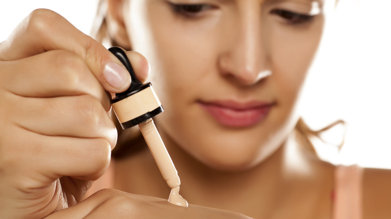 woman dotting foundation on hand 