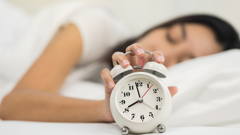 Woman pressing snooze on alarm