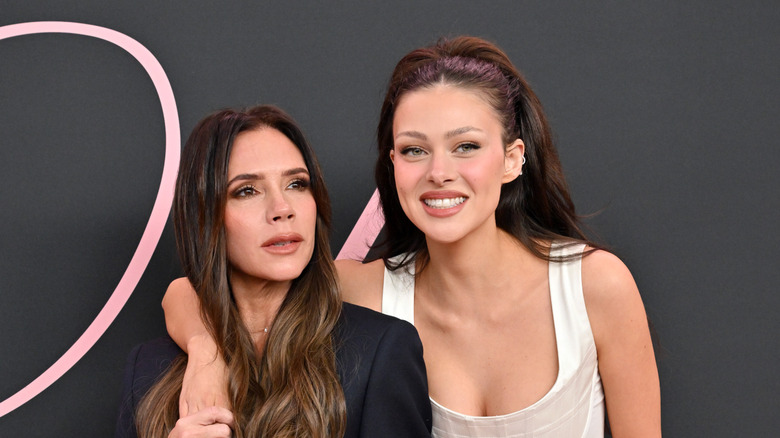 Victoria Beckham wearing black and Nicola Peltz Beckham wearing white