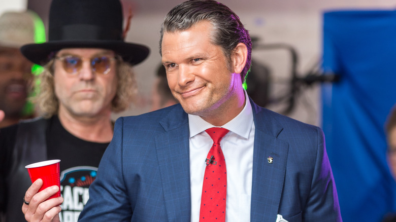 Pete Hegseth smirks while holding a red cup at a Fox event