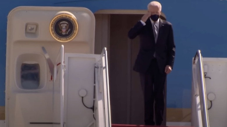 President Joe Biden salutes after tripping on stairs