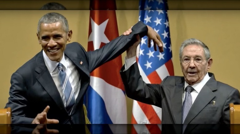 President Barack Obama smiling as President Raul Castro grabs his wrist