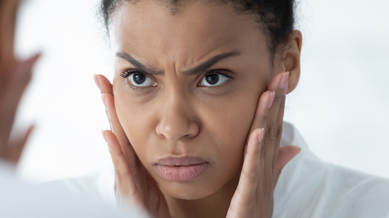 worried woman looking in mirror