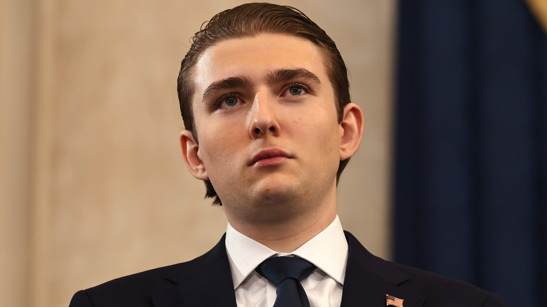 Barron Trump posing and looking up in a suit.