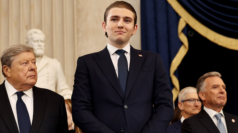 Barron Trump towering over everyone around him with smirk on face