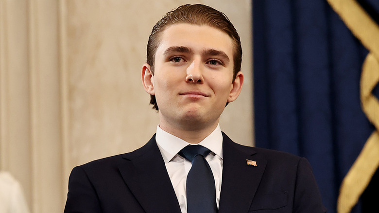 Barron Trump smiles while wearing a suit