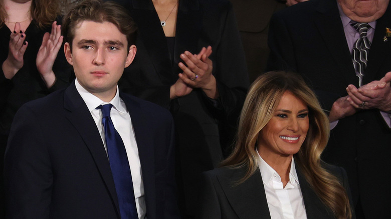 Barron Trump with an awkward smile beside his mother, Melania Trump,