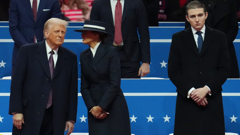 Melania speaking to Donald Trump with Barron Trump standing some distance away