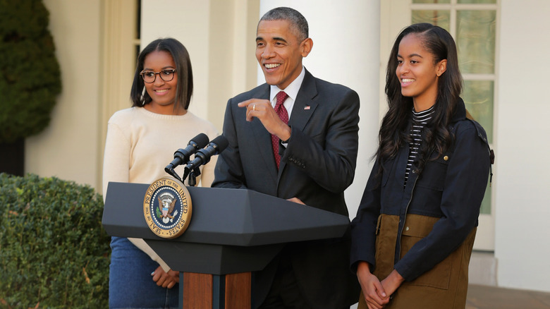 Sasha and Malia Obama stand beside Barack Obama at presidential podium